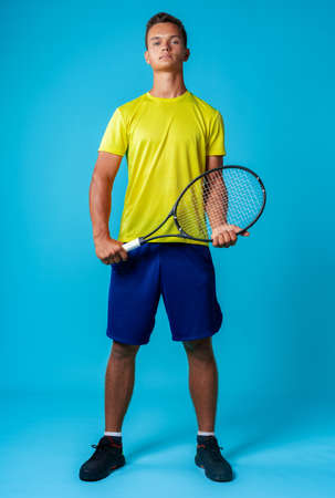 Full length studio portrait of a tennis player man on blue backgroundの写真素材