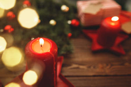 Burning Christmas red candle on brown wooden table