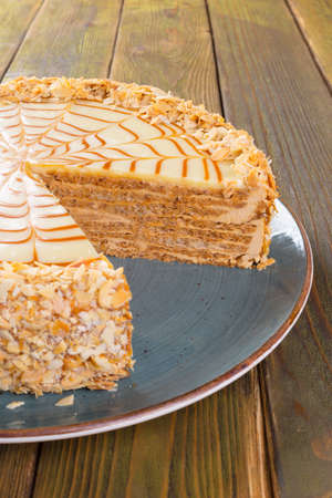 Cut caramel cake on plate on wooden table