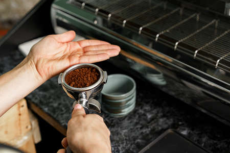 Woman coffee shop worker preparing coffee on professional coffee machineの写真素材
