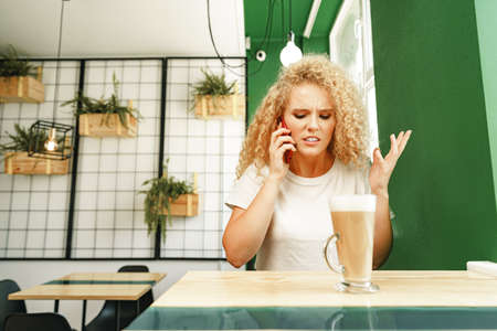 Young beautiful woman talking on the phone in cafeteriaの写真素材