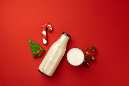 Glass milk bottle and Christmas gingerbread cookies on red backgroundの写真素材