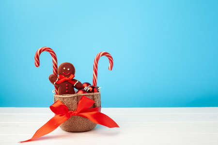 Gingerbread man and candy canes in a basket against blue