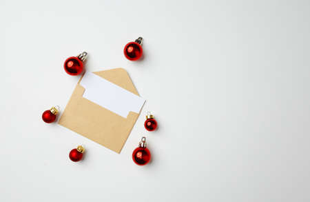 Christmas greeting card in envelope and red baubles on white backgroundの写真素材
