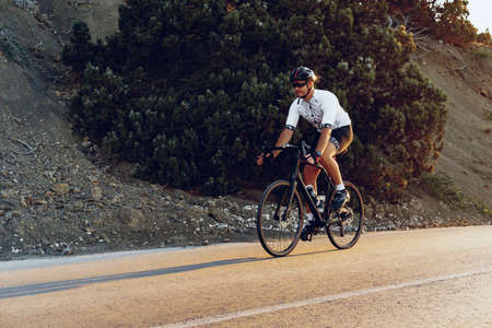 Professional cyclist on a mountain road at sunriseの写真素材