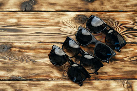 Set of dark sunglasses on brown wooden surface