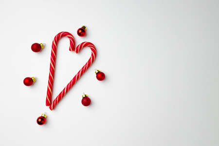 Candy canes and Christmas baubles on white background