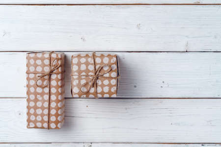 Wrapped Christmas gifts on white wooden board, top view