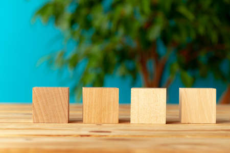 Wooden blocks on desk against blurred plant background