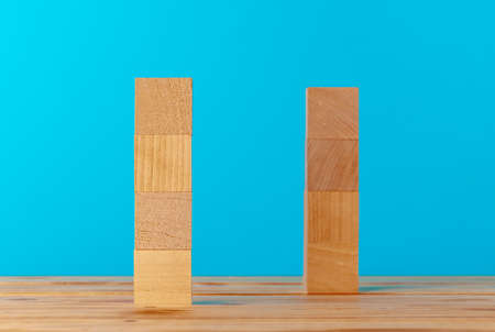 Stacked wooden blocks on wooden desk against blue backgroundの写真素材