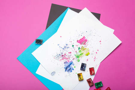 Watercolor paint set with swatches of paint splatter on paper