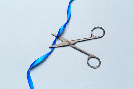 Grand Opening illustrated with scissors and a blue ribbon on a gray backgroundの写真素材