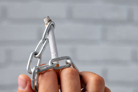 Male hand in metal chains holding cigaretteの写真素材