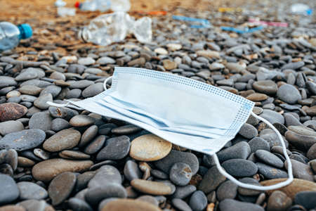 Used medical mask and other garbage left on a beachの写真素材