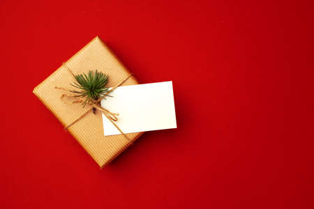 Blank sheet of paper and wrapped present for Christmas celebration on red backgroundの写真素材