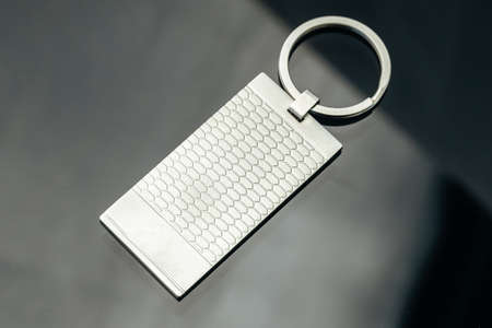 Stylish masculine metal key charm on black glass background