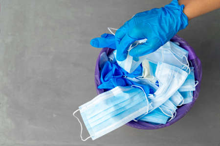 Hand putting used dirty surgical mask to a garbage bin.の写真素材