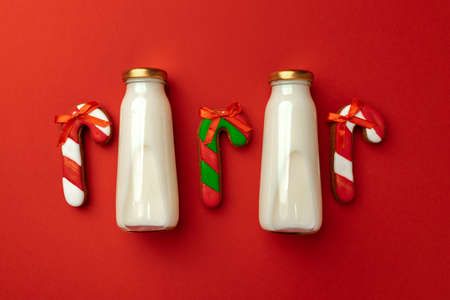 Glass milk bottle and Christmas gingerbread cookies on red background