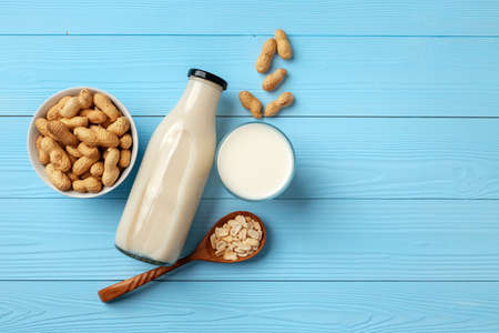 Vegan peanut milk in glass bottle with peanuts on wooden boardの写真素材