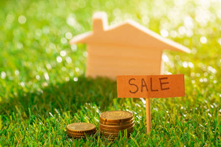 Wooden toy house on grass with sale signの写真素材