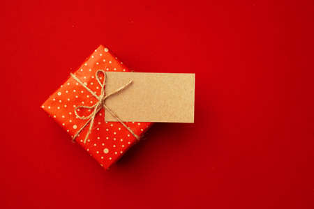 Blank sheet of paper and wrapped present for Christmas celebration on red backgroundの写真素材