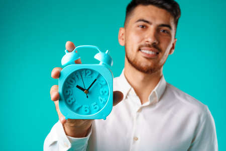 Young mixed race businessman showing alarm clockの写真素材