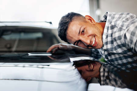Cheerful young man customer buys a new car in a dealershipの写真素材