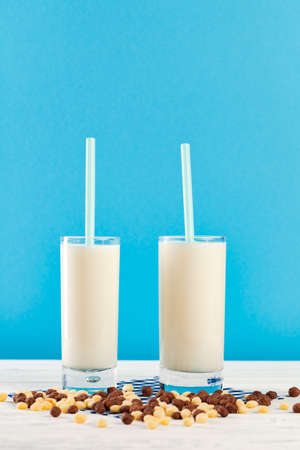 Breakfast cereal balls and milk in glass against blue backgroundの写真素材