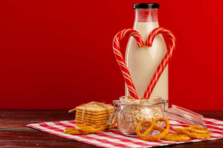 Glass bottle of fresh milk and candy canes on wooden table