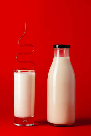 Glass bottle and glass cup with milk front viewの写真素材