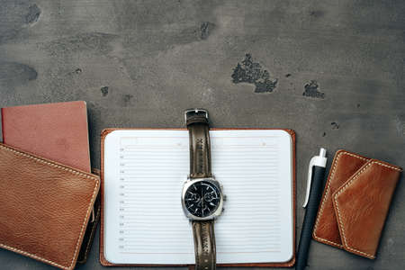Businessmans accessories including notepad, watch and purse on dark grey backgroundの写真素材