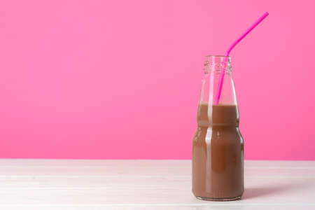 Chocolate milk or milkshake in glass bottle against pink backgroundの写真素材