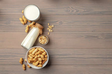 Vegan peanut milk in glass bottle with peanuts on wooden boardの写真素材