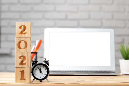 Wooden cubes 2021 Year on working table with open laptop