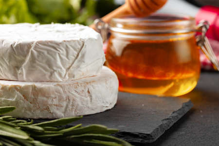 Cheese pieces and honey jar served on dark tableの写真素材