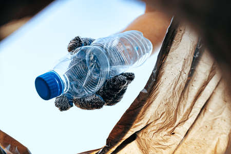 Hand of a man volunteer grabbing plastic litter into a waste bag cleaning up the beachの写真素材