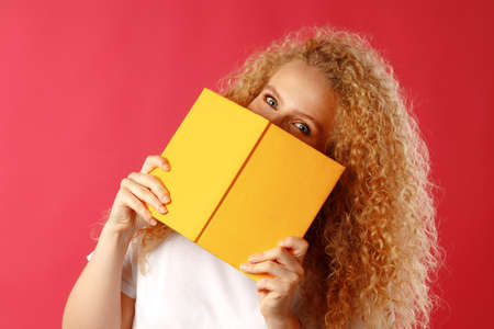 Beautiful young woman hiding behind the book