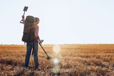 Man with metal detector equipment searching for metal goods in the fieldの写真素材