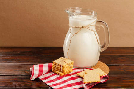 Pitcher of fresh milk on wooden table against beige backgroundの写真素材