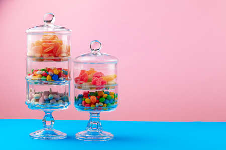 Glass containers with candies against pink backgroundの写真素材