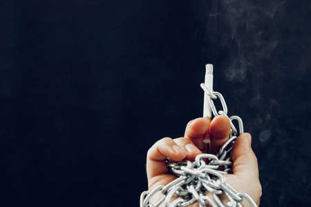 Male hand in metal chains holding cigaretteの写真素材