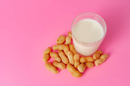 Non-dairy vegan milk made of nuts in glassware against pink backgroundの写真素材