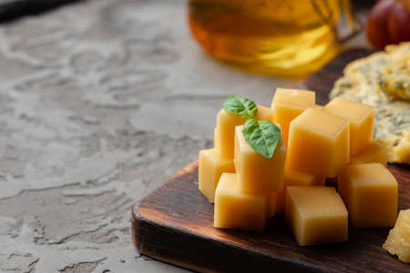 Cheese pieces and honey jar served on dark table