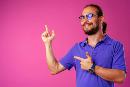 Casual long-haired man pointing to copy space