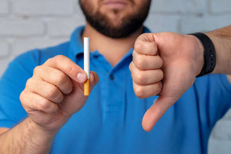 Man in blue short gesturing smoking is badの写真素材