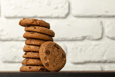 Pile of chocolate chip cookies against white brick wall