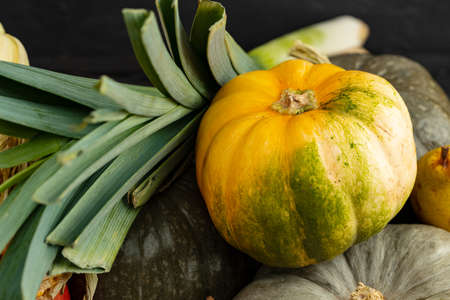 Stacked green pumpkins and greens on dark background