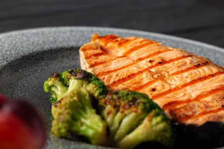 Grilled salmon steak with broccoli on grey plateの写真素材