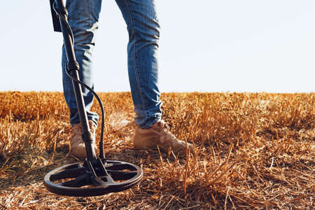Man with metal detector equipment searching for metal goods in the fieldの写真素材