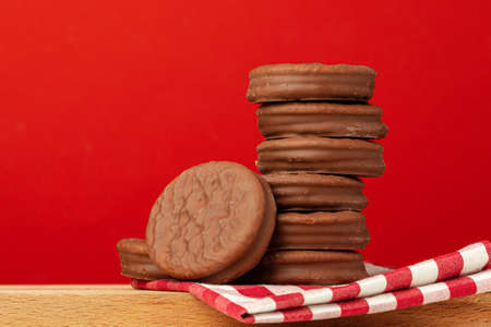 Glazed chocolate cookies stack on red background